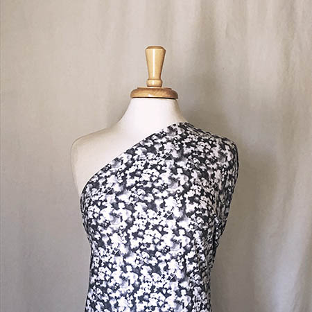 gray and white floral knit fabric draped over a mannequin